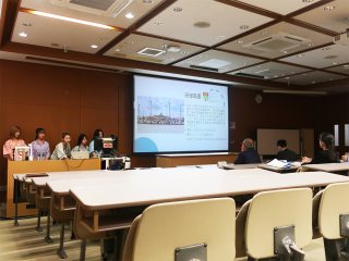 UKMの学生が選んだそれぞれのイメージカラーのバジュクルンを着用し発表する学生